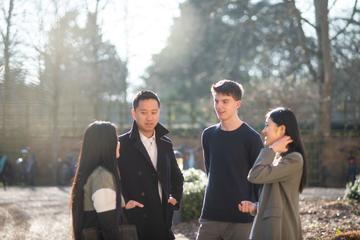 Three students standing outside chatting with a tutor. 